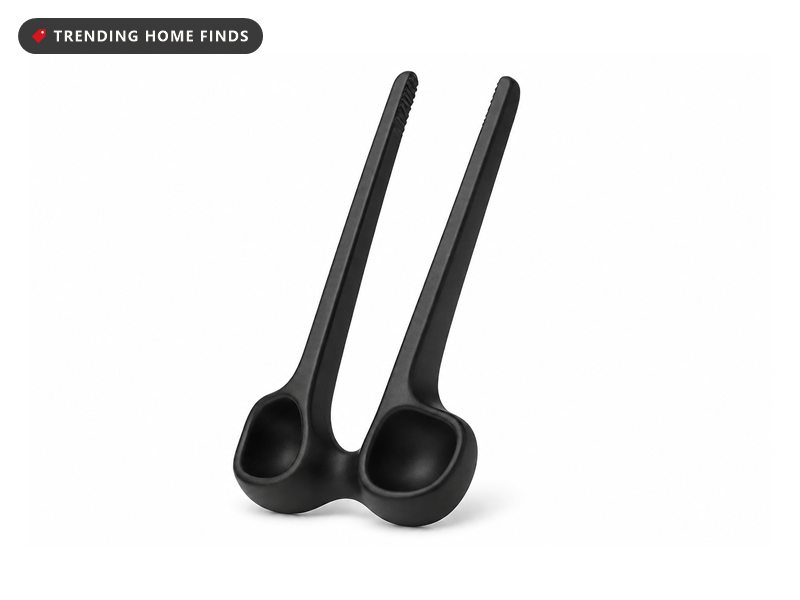 Black finger mounted chopsticks pinching a snack between two fingers