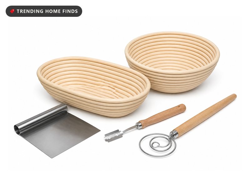 Sourdough kit laid out on white: round and oval rattan bannetons with scored loaves, starter jar, lame, scraper and whisk.