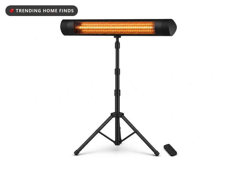 Black standing infrared patio heater on a tripod with its carbon tube glowing orange