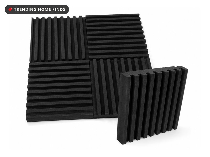 Stack of black grooved acoustic foam panels two inches thick, with one panel propped upright showing its slotted profile