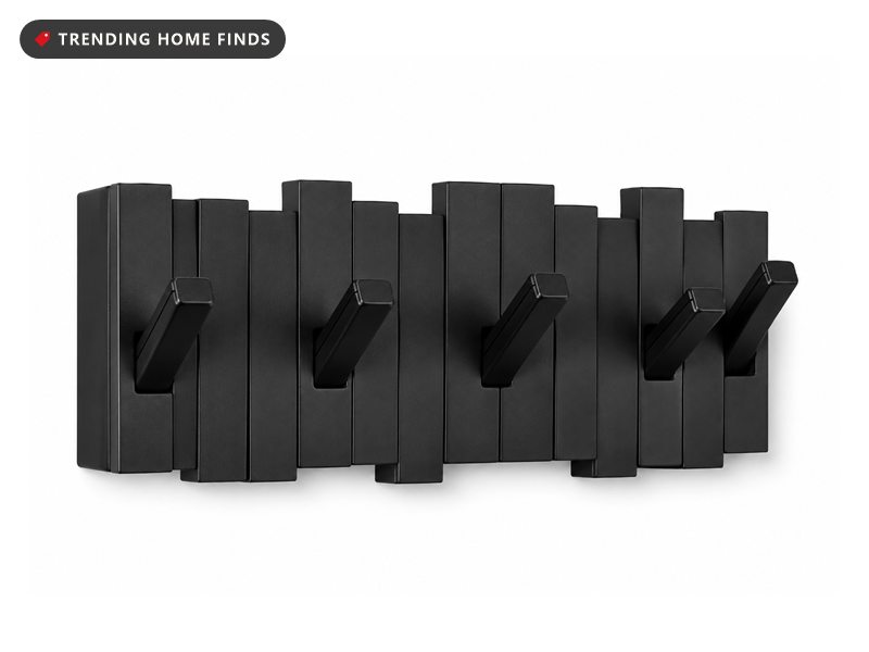 Black Umbra Sticks wall mounted coat rack with five angled retractable pegs on a slatted backing