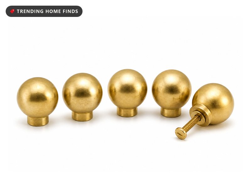 A hand-free close view of round brass knobs on cream shaker cabinet doors in late golden hour light, a small kitchen cabinet makeover detail.