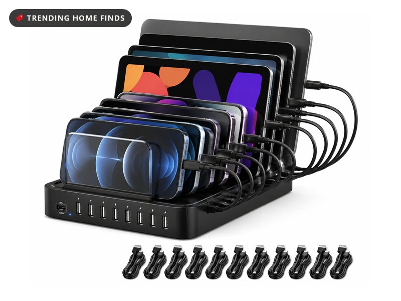 Black ten-port USB charging station holding several phones and tablets upright in slots, with ten charging cables and dividers