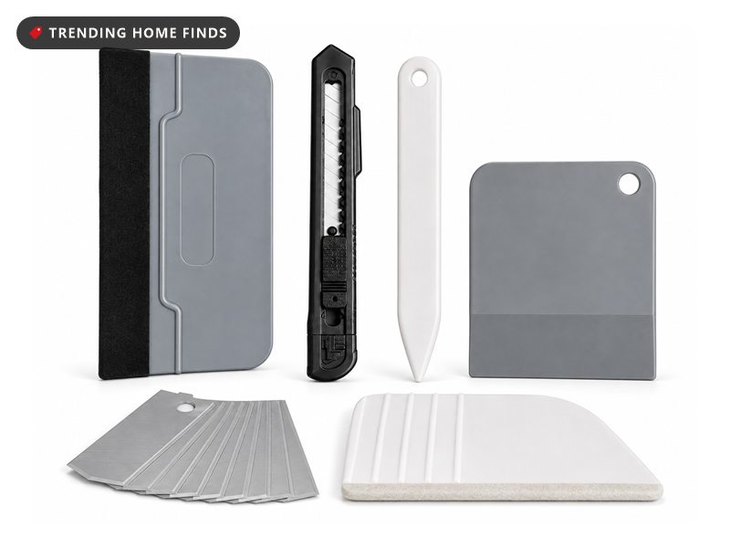 Wallpaper smoothing tool kit with a grey squeegee, utility knife, scraper, trim guide and a pack of spare blades