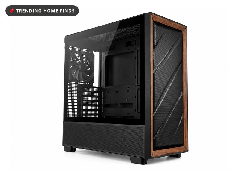 Black mid tower with a walnut wood front panel on a cozy gaming setup desk beside a trailing plant, flat overcast light from the window.