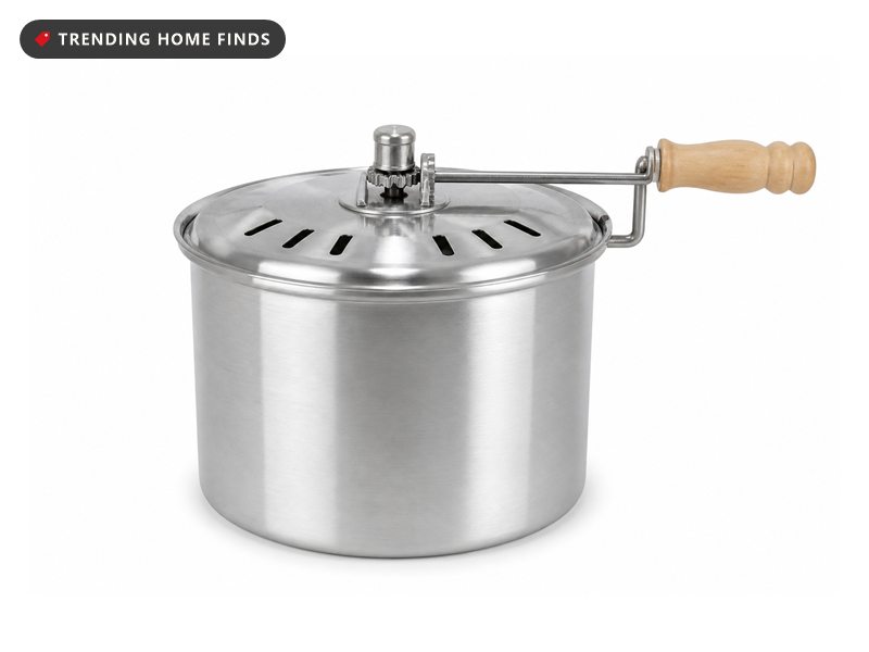 Stainless steel stovetop popcorn popper with a wooden crank handle and lid, on a white background.