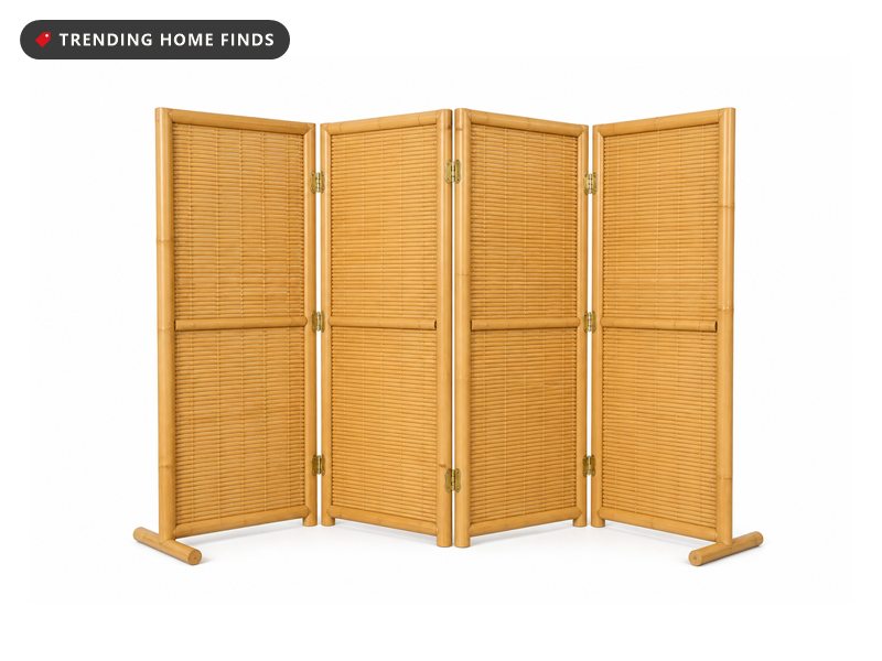 A natural bamboo four panel folding screen standing open in a shallow zigzag with woven slat panels and brass hinges.