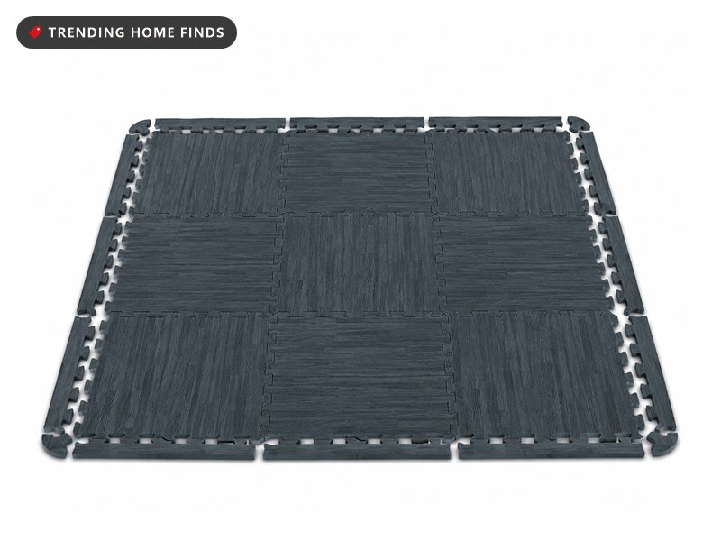 Nine dark gray wood grain interlocking foam floor tiles assembled into a square mat with finished border strips around the edges